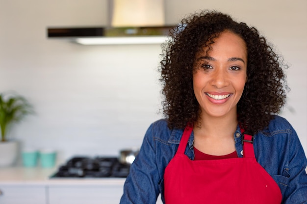 Portrait d'une femme afro-américaine heureuse portant un tablier dans la cuisine