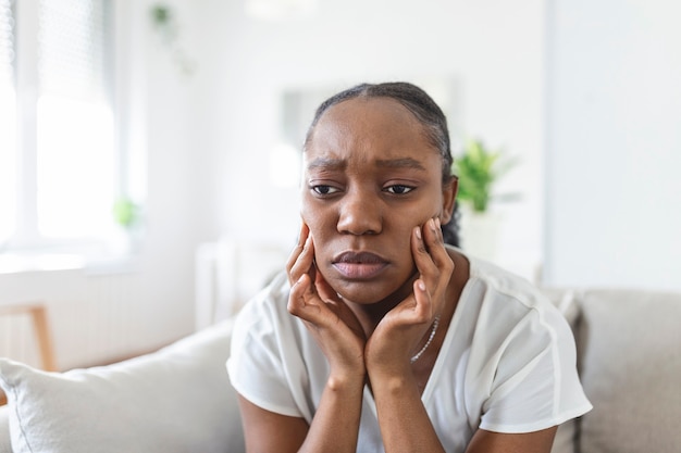 Portrait d'une femme afro-américaine malheureuse souffrant de maux de dents à la maison. Concept de soins de santé, de santé dentaire et de problème. Stock photo
