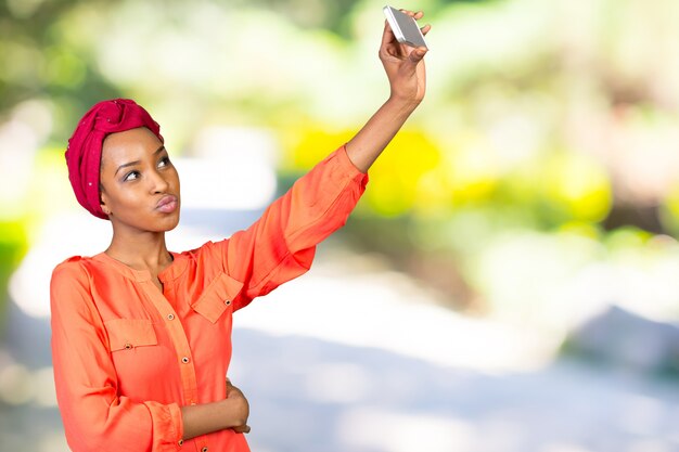 Portrait d'une femme afro-américaine souriante faisant une photo de selfie