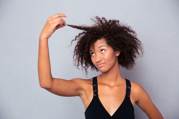 Portrait de femme afro-américaine touchant ses cheveux sur mur gris