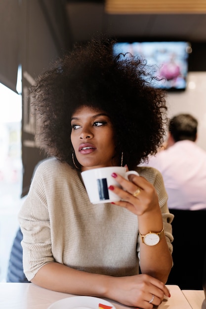 Portrait d'une femme afro séduisante dans un café. Concept de femme d'affaires