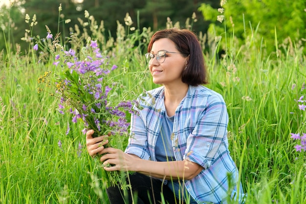 Portrait d'une femme d'âge moyen avec un bouquet de fleurs sauvages dans la nature