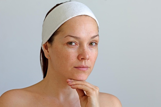 Portrait d'une femme d'âge moyen caucasienne sérieuse sans maquillage avec bande sur la tête tenant le menton par ha