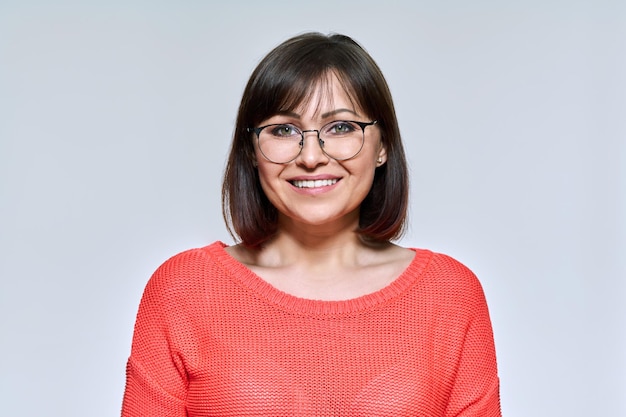 Portrait de femme d'âge moyen regardant la caméra sur fond de studio clair