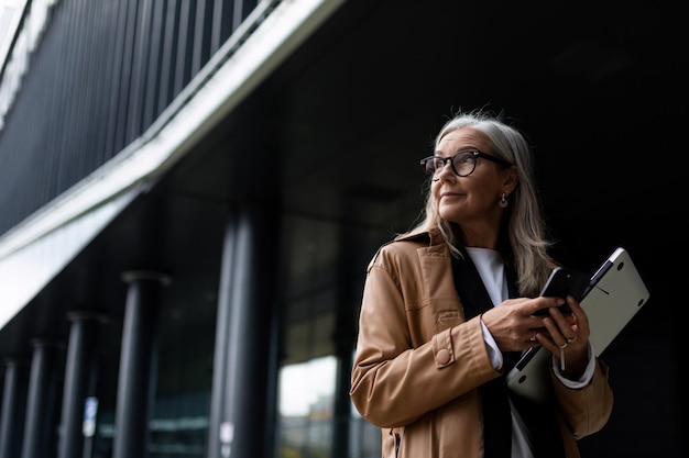 Portrait d'une femme âgée d'affaires élégante réussie sur le fond d'un centre de bureau moderne