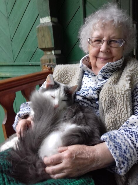 Portrait d'une femme âgée assise avec un chat à la maison