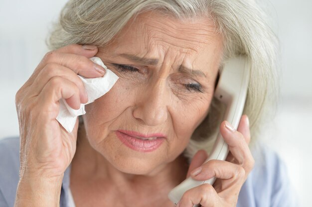 Portrait d'une femme âgée bouleversée appelant un médecin