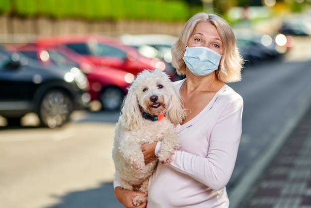 Portrait femme âgée avec un chien à l'extérieur d'un masque antivirus