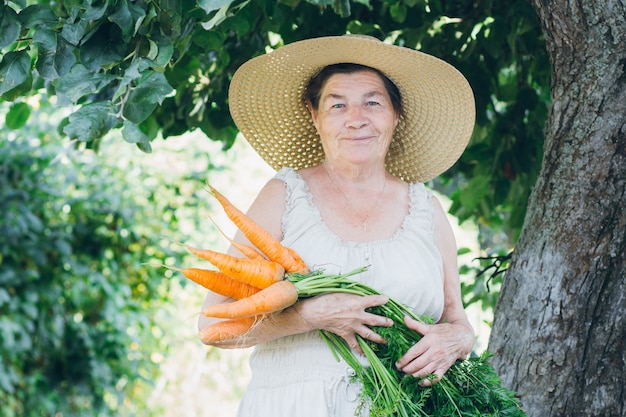 Portrait d'une femme âgée dans un chapeau tenant une carotte