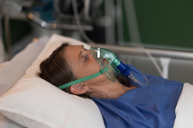 Portrait d'une femme âgée dans un lit d'hôpital portant un masque à oxygène dans un état d'inconscience paisible