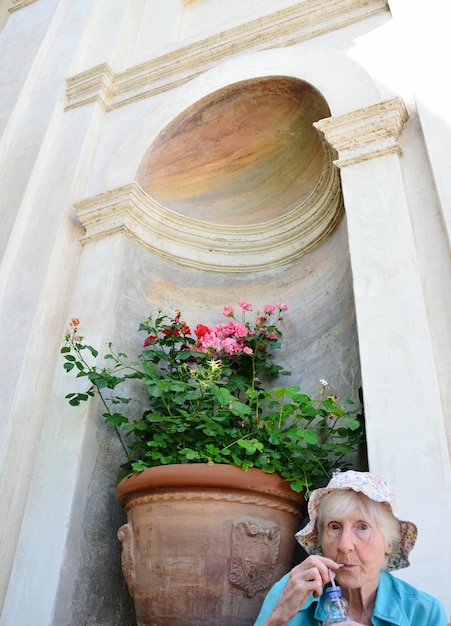 Photo portrait d'une femme âgée debout contre une plante en pot