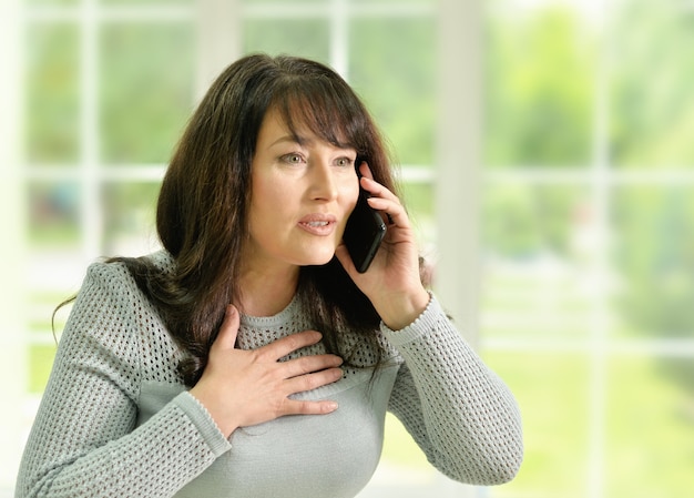 Portrait d'une femme âgée heureuse parlant au téléphone