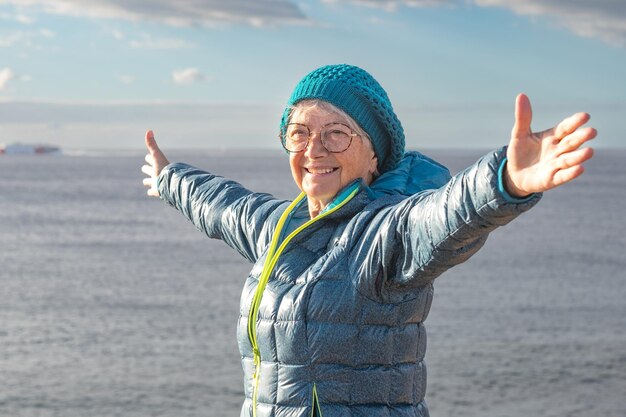 Photo portrait d'une femme âgée souriante à bras ouverts lors d'une excursion en bord de mer en plein air regardant l'horizon femme séduisante mature appréciant la liberté de l'aventure et des vacances saines