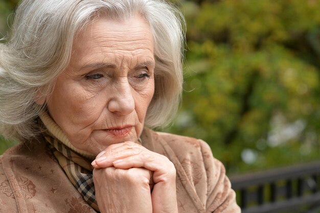 Portrait d'une femme âgée triste dans le parc d'automne