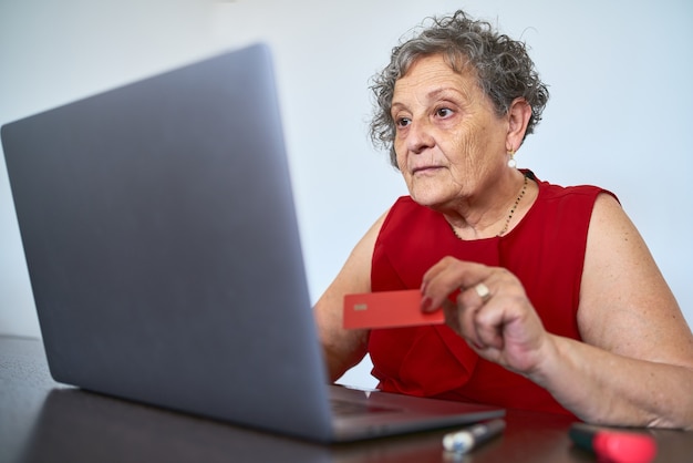 Portrait d'une femme âgée utilisant une carte de crédit pour acheter en ligne