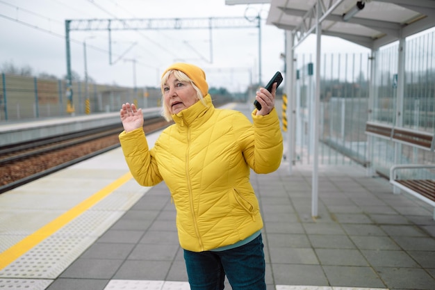 Photo portrait d'une femme âgée utilisant un téléphone portable en attendant à la station de tramway photo de haute qualité