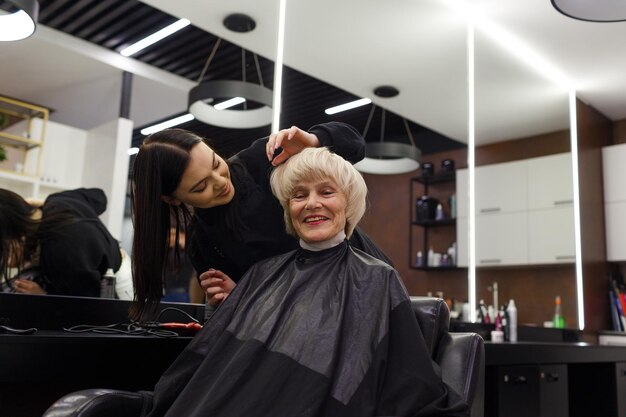 Portrait d'une femme âgée visitant un coiffeur professionnel Un coiffeur expérimenté fait la coiffure d'un client