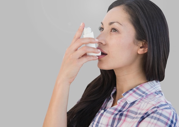Portrait de femme à l'aide d'inhalateur pour l'asthme avec fond gris