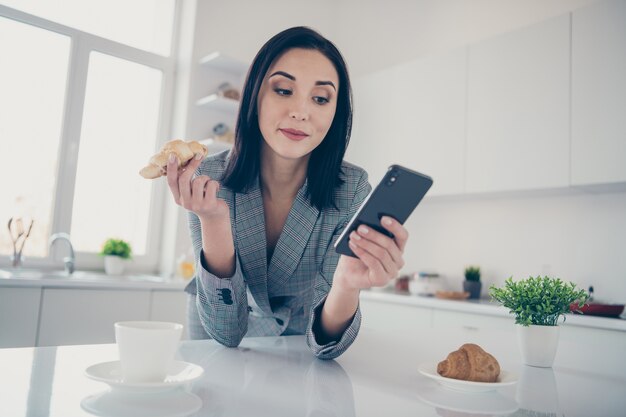 portrait femme à l'aide de téléphone tout en prenant le petit déjeuner