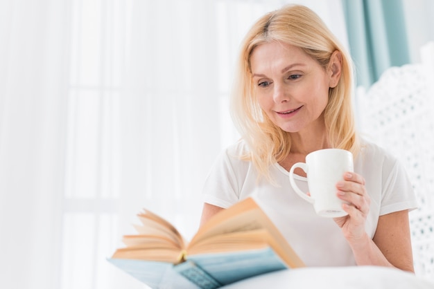 Portrait, de, femme aînée, lecture livre, dans lit