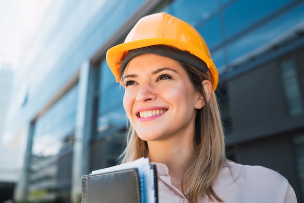 Photo portrait de femme architecte professionnelle portant un casque jaune et debout à l'extérieur. concept d'ingénieur et d'architecte.