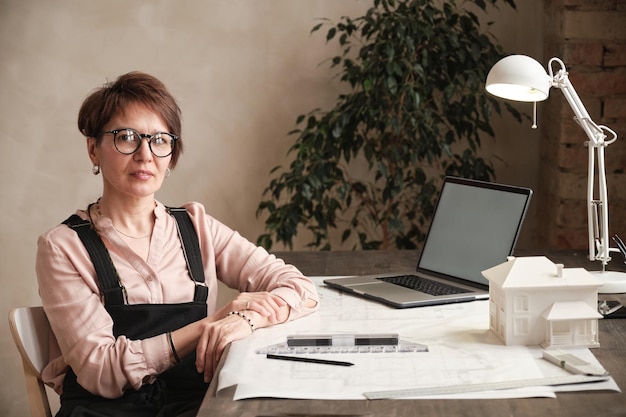 Portrait d'une femme architecte réussie assise à table