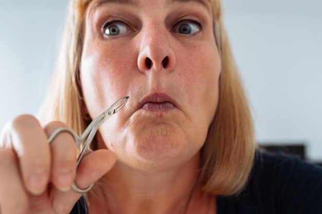 Portrait femme arrachant les poils du visage avec des pincettes