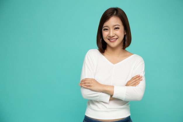 Portrait de femme asiatique avec les bras croisés sur fond vert.