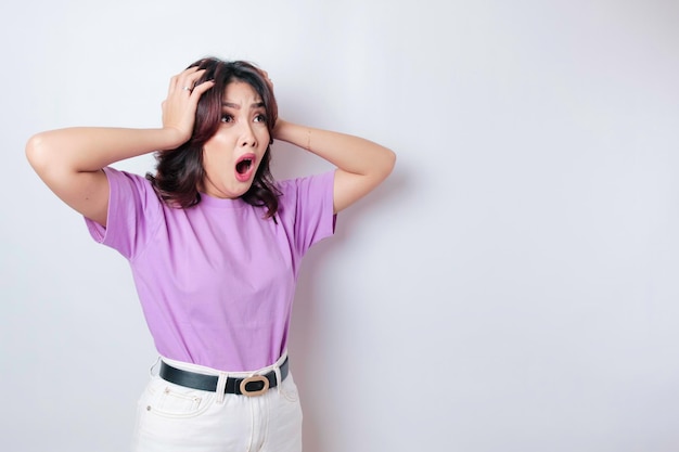 Un portrait d'une femme asiatique choquée portant un t-shirt violet lilas isolé par un fond blanc