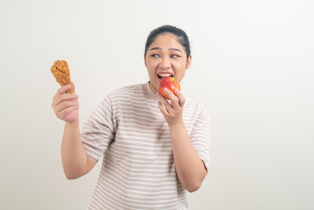 portrait femme asiatique avec du poulet frit et de la pomme à portée de main pour le choix