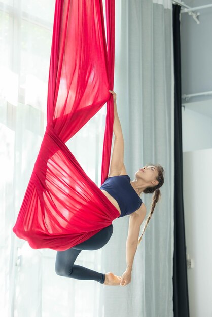 Photo portrait d'une femme asiatique heureuse en cours de yoga aérien une femme asiatique faisant des exercices d'étirement de yoga à la mouche