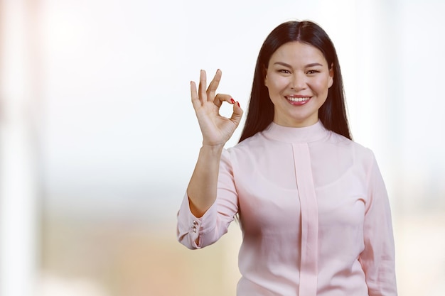 Portrait d'une femme asiatique heureuse montrant un geste correct