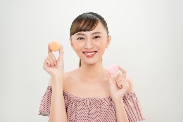 Portrait d'une femme asiatique heureuse tenant des macarons