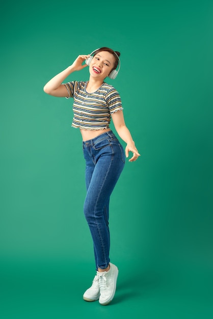 Portrait De Femme Asiatique Joyeuse Sur Des Vêtements Décontractés Dansant Et écoutant De La Musique Avec Un Casque Sur Vert.