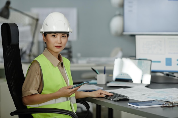 Portrait d'une femme asiatique portant un casque sur le lieu de travail au bureau et regardant la caméra avec une expression faciale sérieuse.