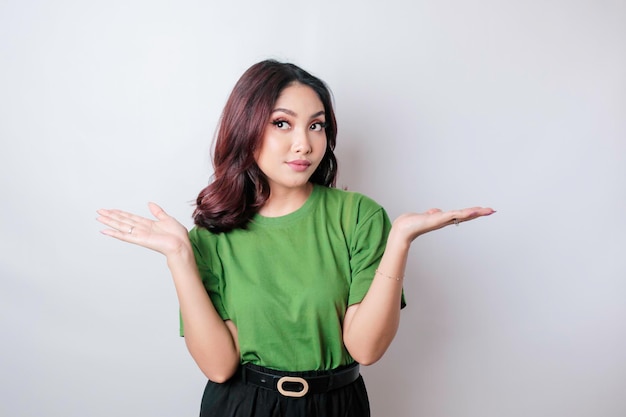 Un portrait d'une femme asiatique portant un t-shirt vert a l'air si confus isolé par un fond blanc