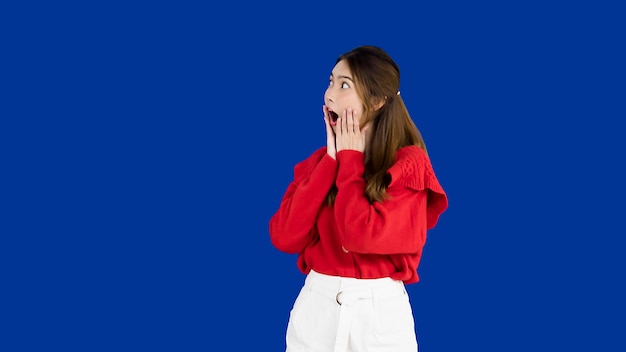 Portrait d'une femme asiatique regardant de côté avec une expression surprise sur son visage sur l'écran bleu