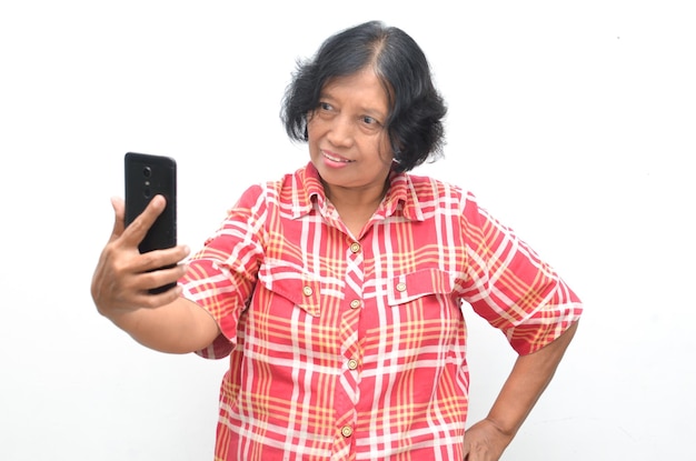 Portrait d'une femme asiatique senior extatique heureuse tenant et montrant l'écran du téléphone