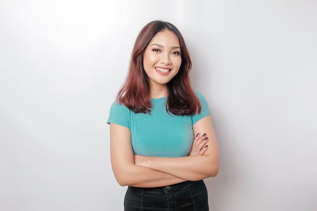 Portrait d'une femme asiatique souriante confiante portant une chemise bleue debout avec les bras croisés et regardant la caméra isolée sur fond blanc