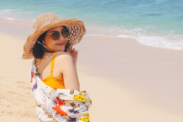 Portrait d'une femme asiatique souriante heureuse sur la plage sur une belle jolie fille asiatique décontractée regardant loin et souriant en riant La plage magnifique au ciel lumineux