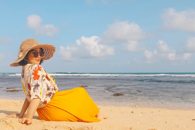 Portrait d'une femme asiatique souriante heureuse sur la plage porter un chapeau