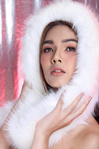 Portrait de femme asiatique souriante à la mode maquillage Style fourrure blanche cheveux noirs, éclairage de studio espace de copie de fond en tissu argenté rose, Concept de luxe pour rejoindre l'événement social de nuit