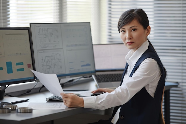 Portrait d'une femme asiatique en tant qu'ingénieure utilisant un ordinateur au bureau et regardant l'espace de copie de la caméra