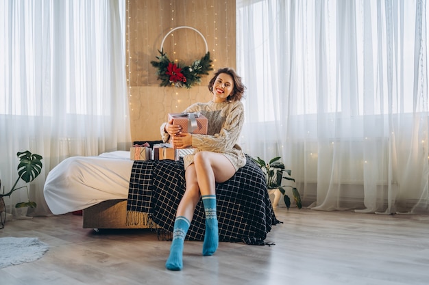 Portrait femme assise dans son lit avec des cadeaux autour