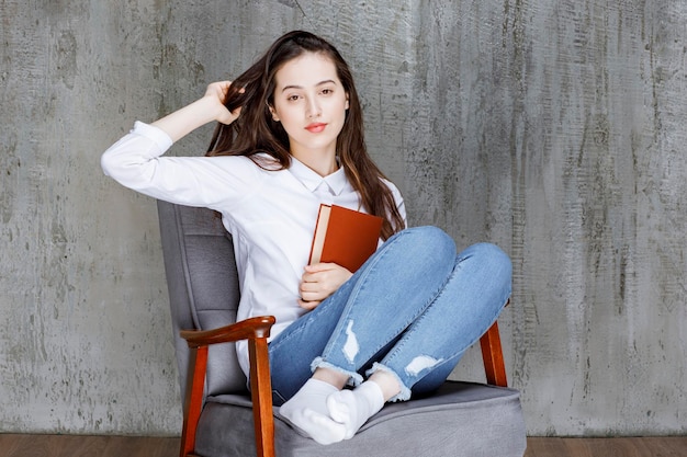 Portrait de femme assise sur un fauteuil avec pose de livre. Photo de haute qualité