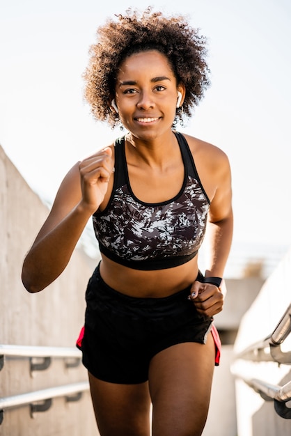 Portrait de femme athlète afro en cours d'exécution et faire de l'exercice à l'extérieur. Sport et mode de vie sain.