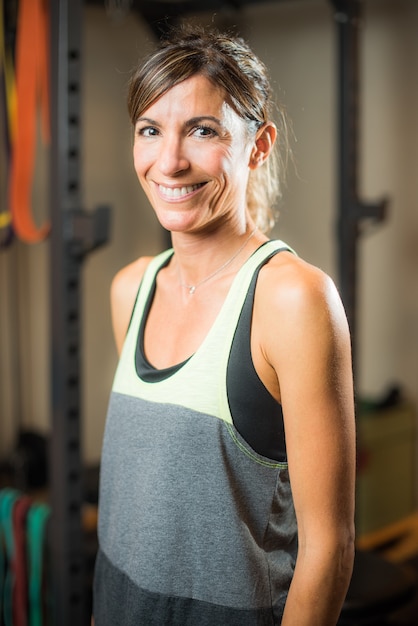 Portrait d'une femme athlète joyeuse dans une salle de sport en regardant la caméra. Concept de personnes dans la salle de gym.