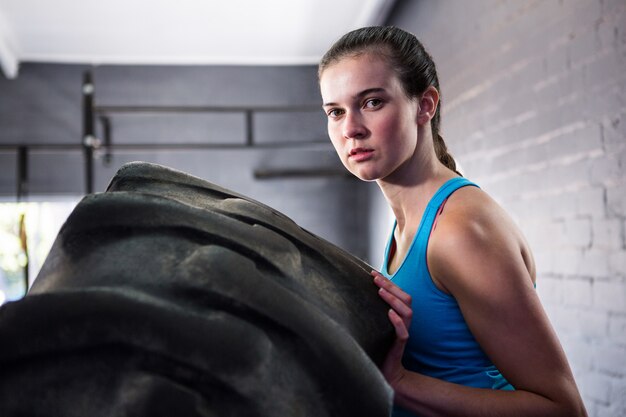 Portrait, femme, athlète, pousser, pneu, Gymnase