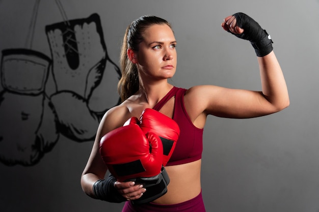 Portrait d'une femme athlétique qui montre des muscles après un entraînement de boxe