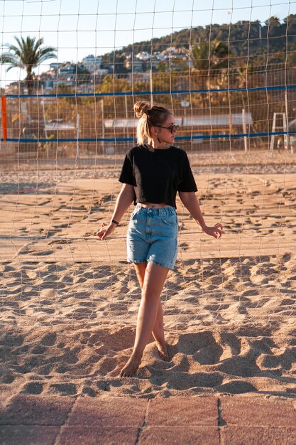 Portrait de femme attirante près du filet de volley-ball sur la photo verticale de plage